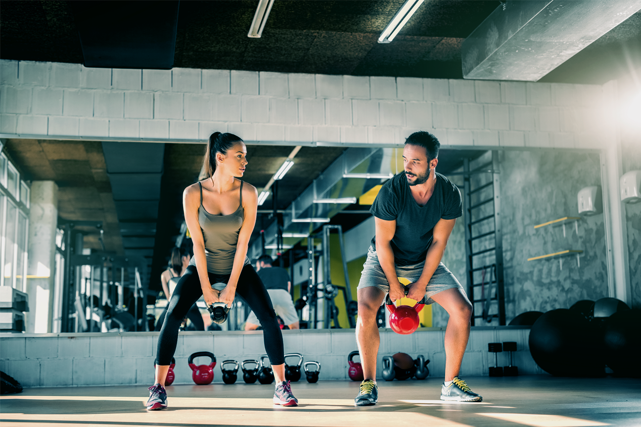 Two people doing kettlebell swings, blog discusses how to encourage your family to live a healthy lifestyle